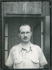 Robert van Gulik voor zijn studeerkamer in Chungking (Chongqing, 1946) met op het bord boven de deur de naam van zijn studeerkamer. De drie Chinese karakters betekenen: ‘Hut waar de maan wordt bezongen.’